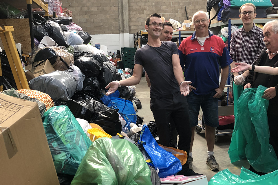 People standing next to bags of toys in a large warehouse