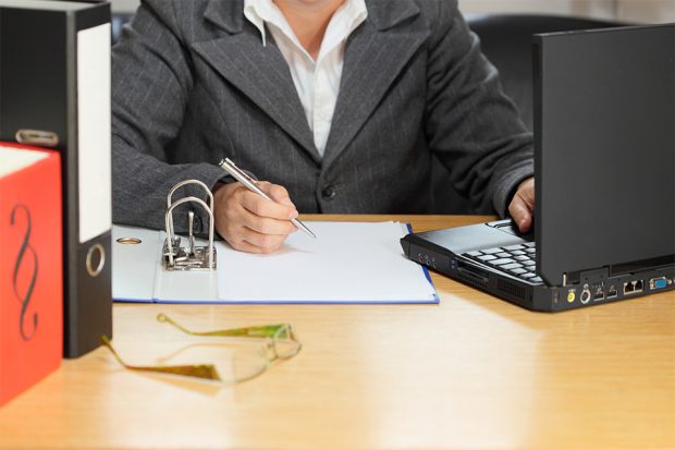 Woman working on a laptop and making notes