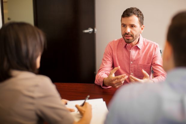 Man in an interview sat behind a desk