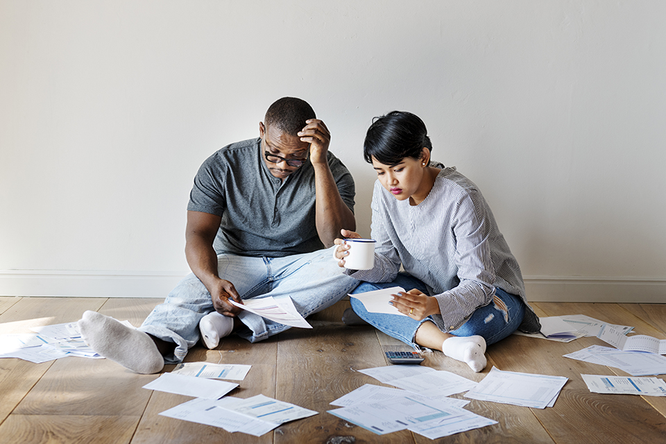 A young couple sat on the floor looking at paperwork