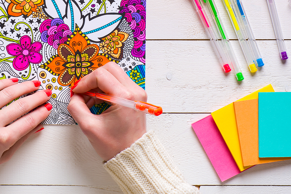 Woman colouring in a mindfulness colouring book with a pen