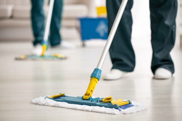 Close-up of a floor mop on the floor held by a cleaner