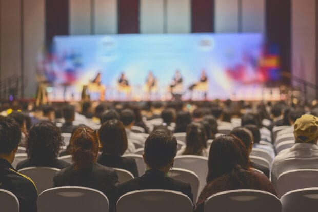 Rear view of audience listening to a presentation at a conference hall