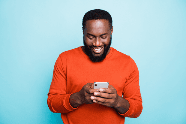 man holding and looking at mobile telephone and smiling